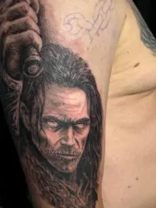 Realistisches Black-&-Grey-Tattoo des nordischen Gottes Loki mit langem Haar und intensivem Blick