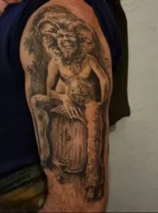 ealistisches Black-&-Grey-Tattoo des griechischen Gottes Pan mit Hörnern auf dem Oberarm von Ozzy in Hamburg