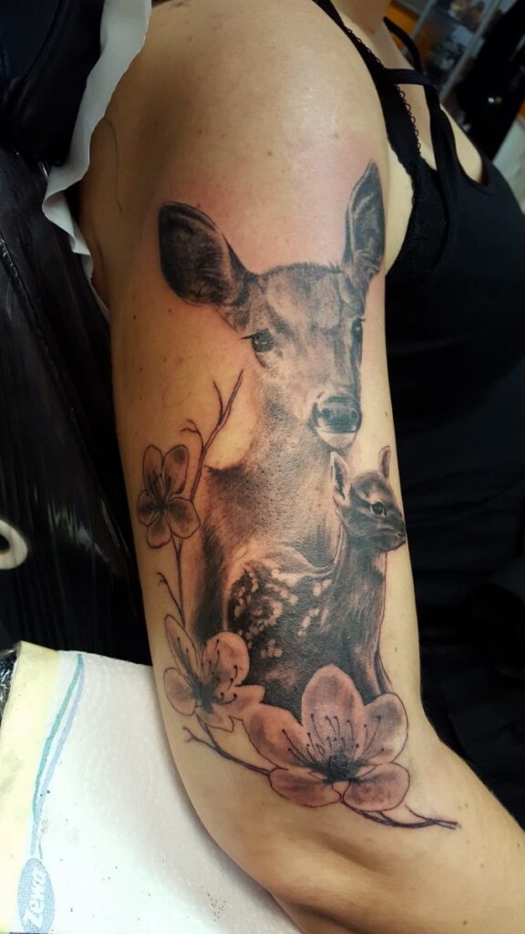 Reh-Tattoo einer Reh-Mutter mit Rehbaby mit Blumenmotiv auf dem Unterarm. Tattoo in Hamburg von Ozzy gestochen